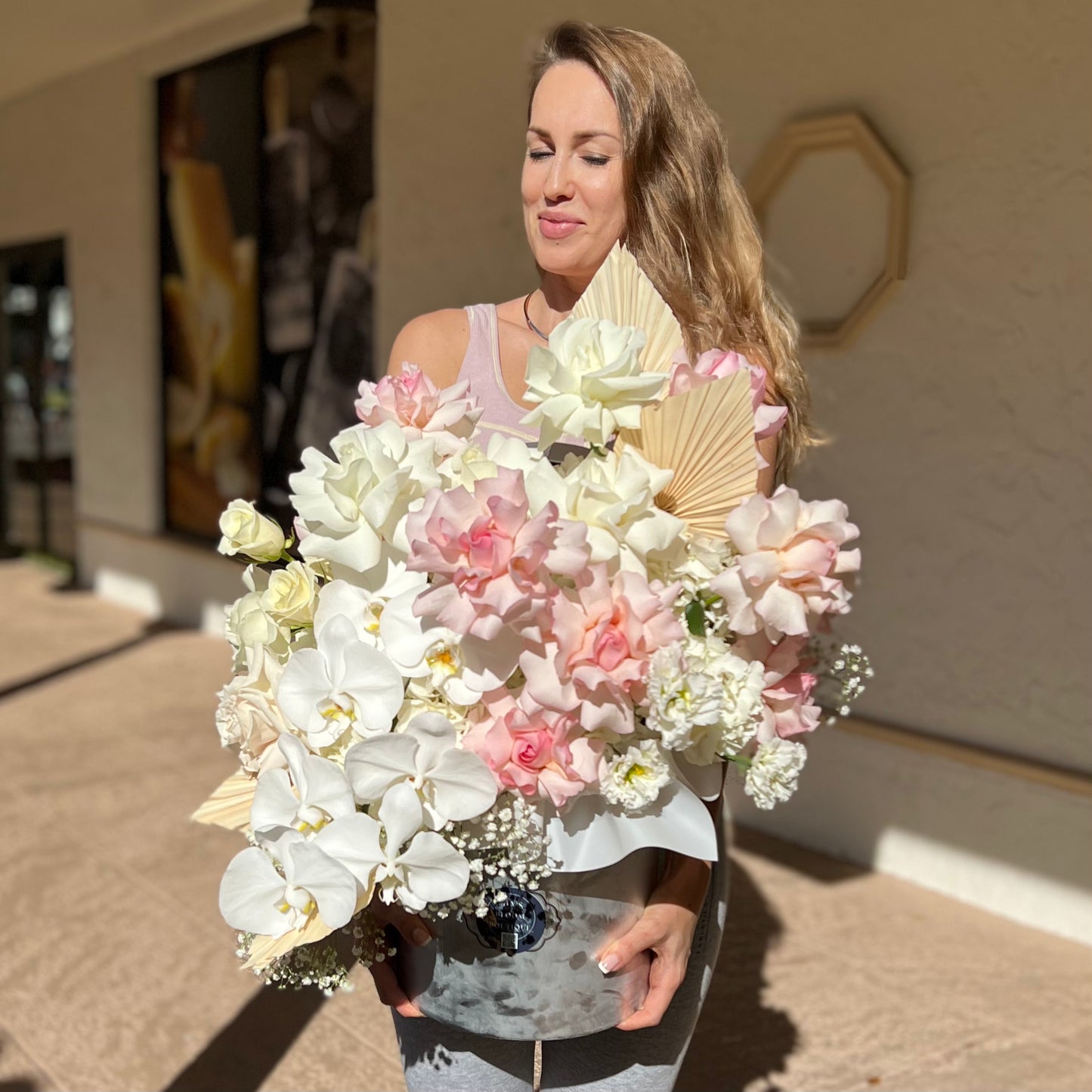 A woman holding bright color bouquet of flowers in a gray large box