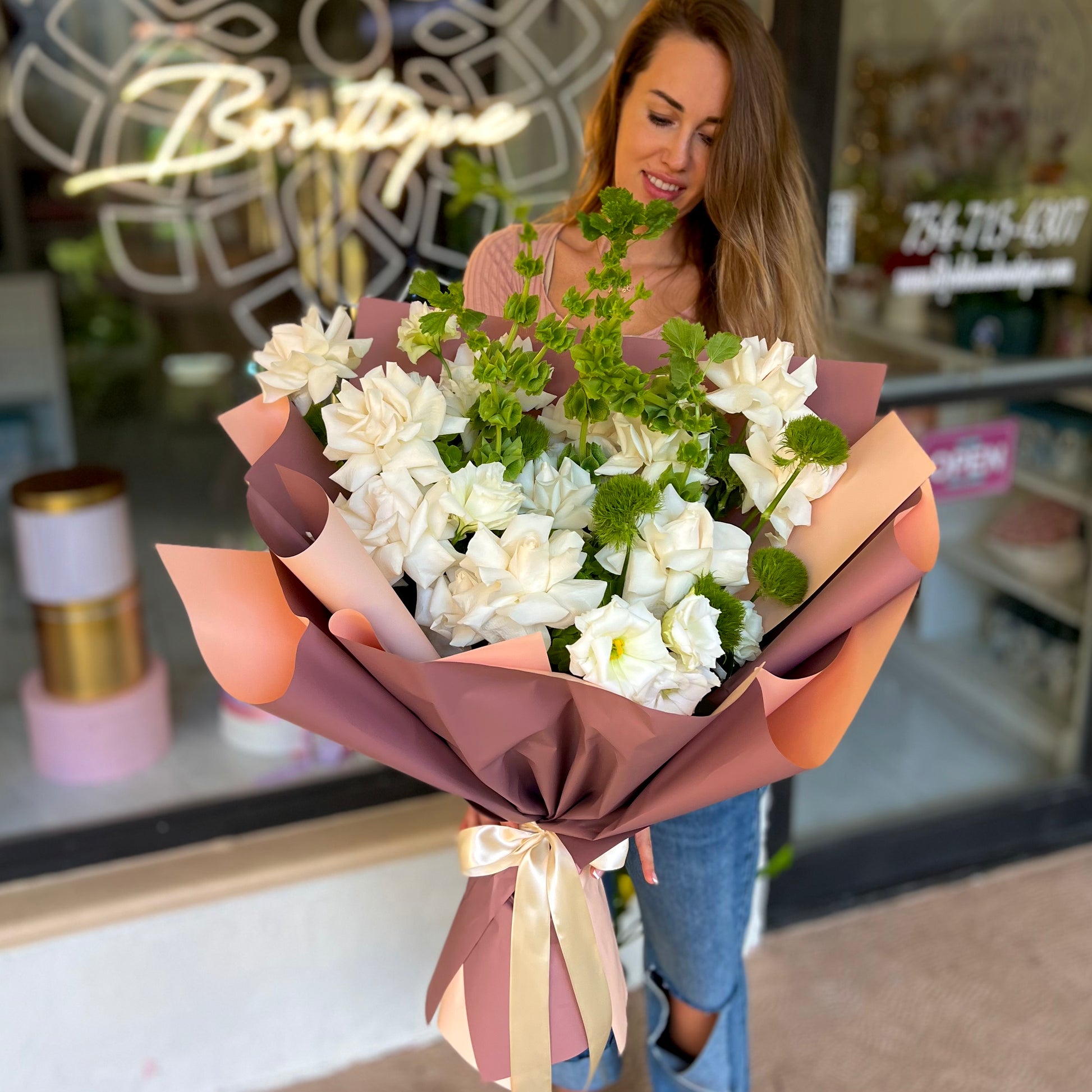 Women with long brown hair holding white flowers outside store front