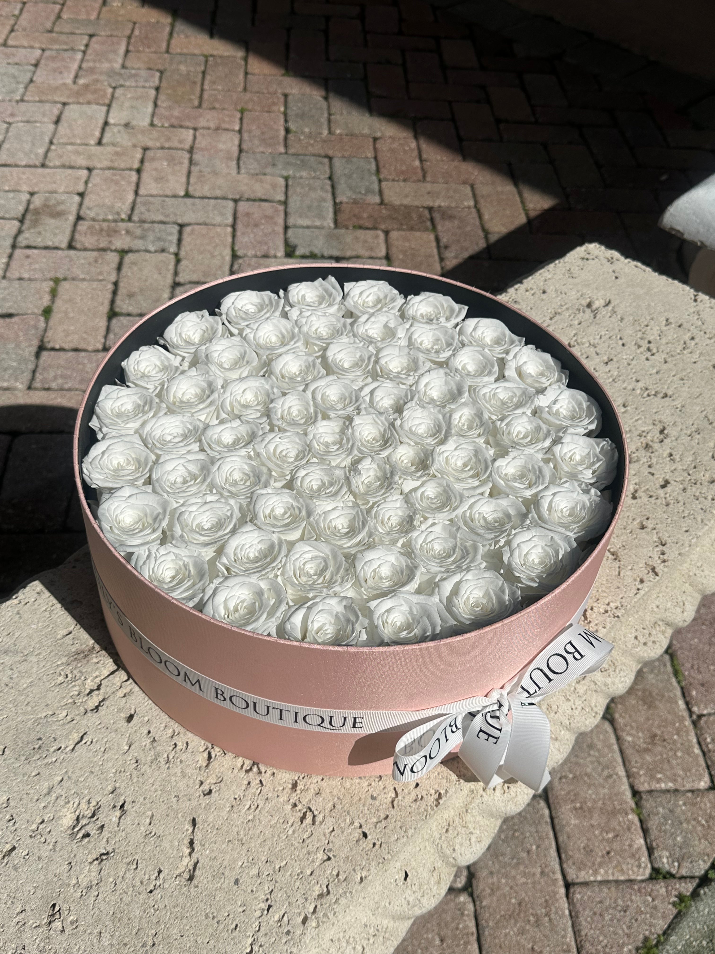 Round box of preserved roses on a concrete bench