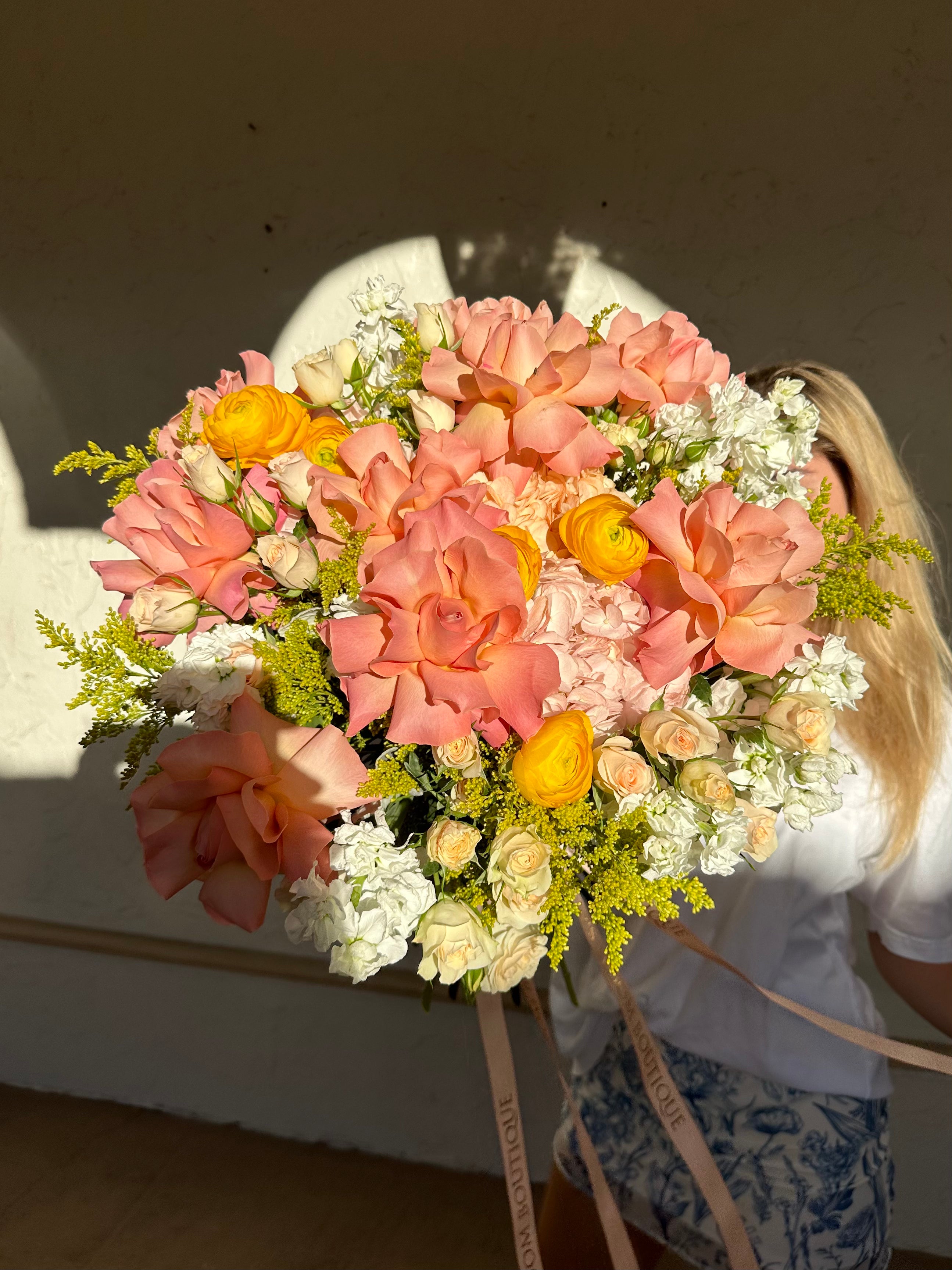 a girl holding gorgeous bouquet of mixed flowers peach and white color