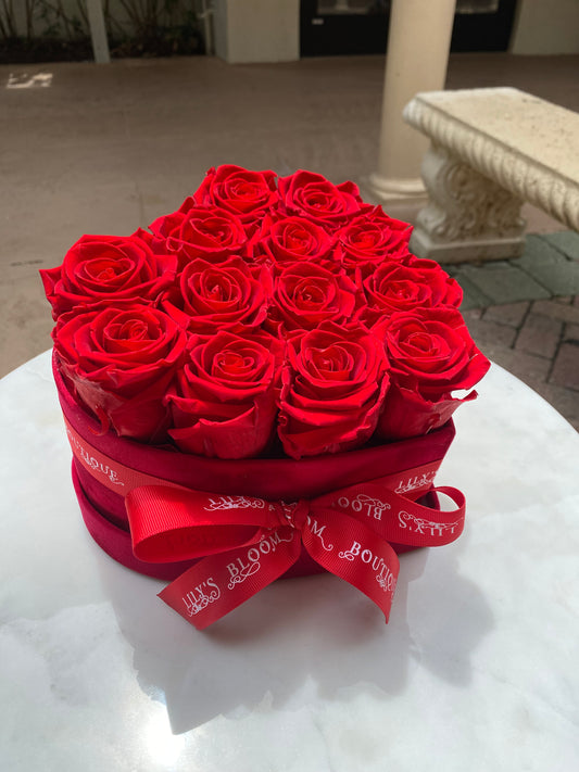 12 Roses in a box with red Ribbon on a table