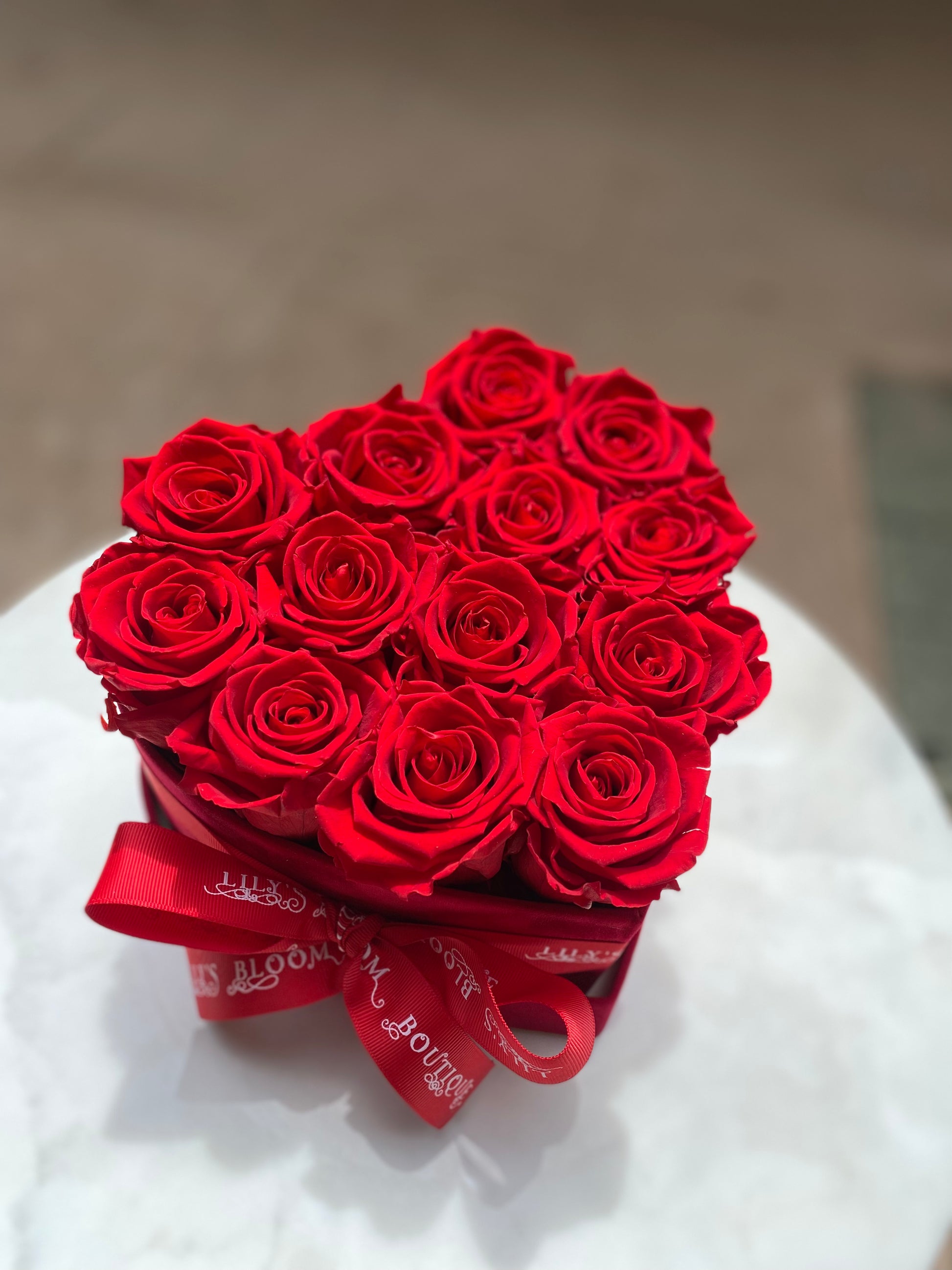 Red Roses in a box with red Ribbon on a table