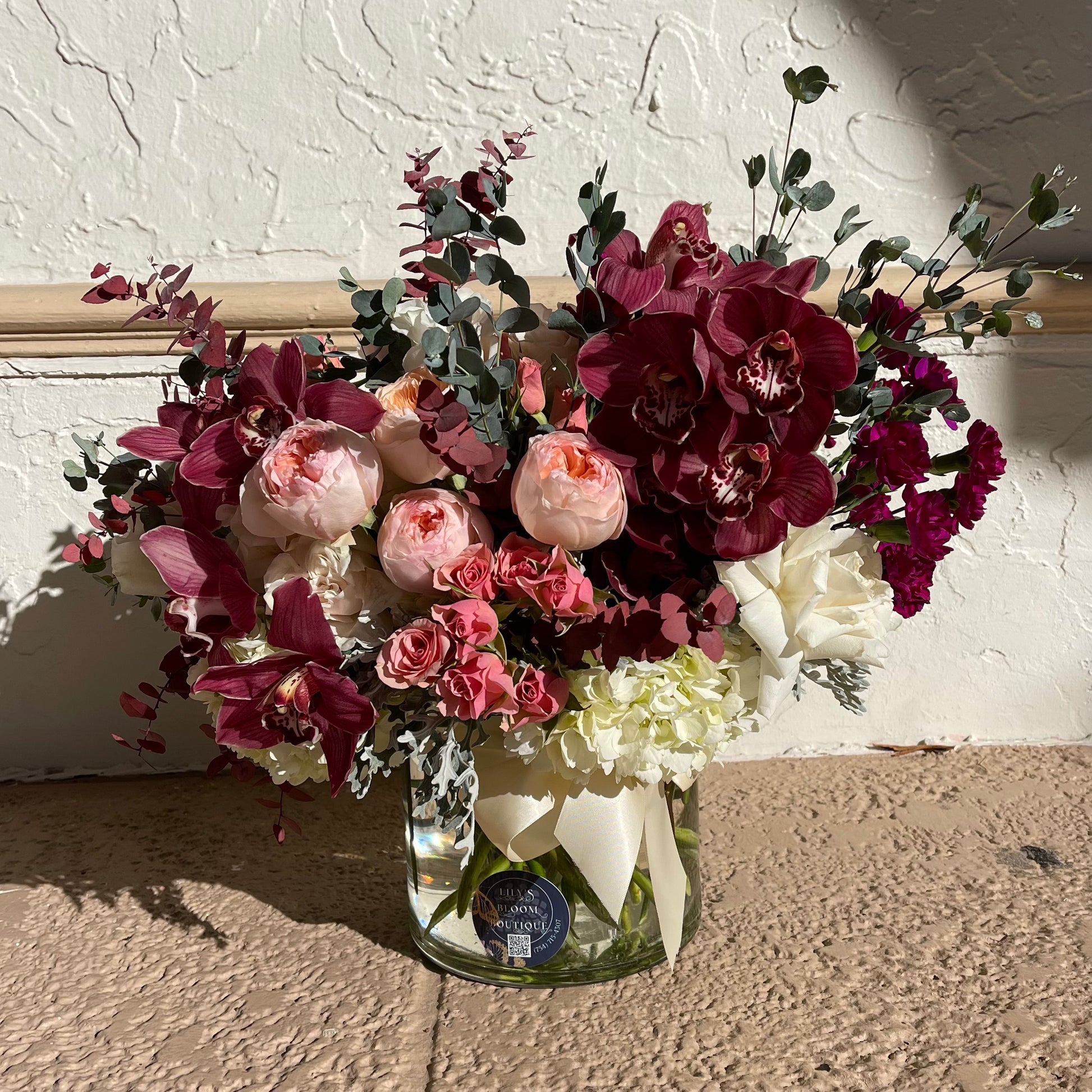 The stunning bouquet of flowers with orchids and roses in a clear glass vase