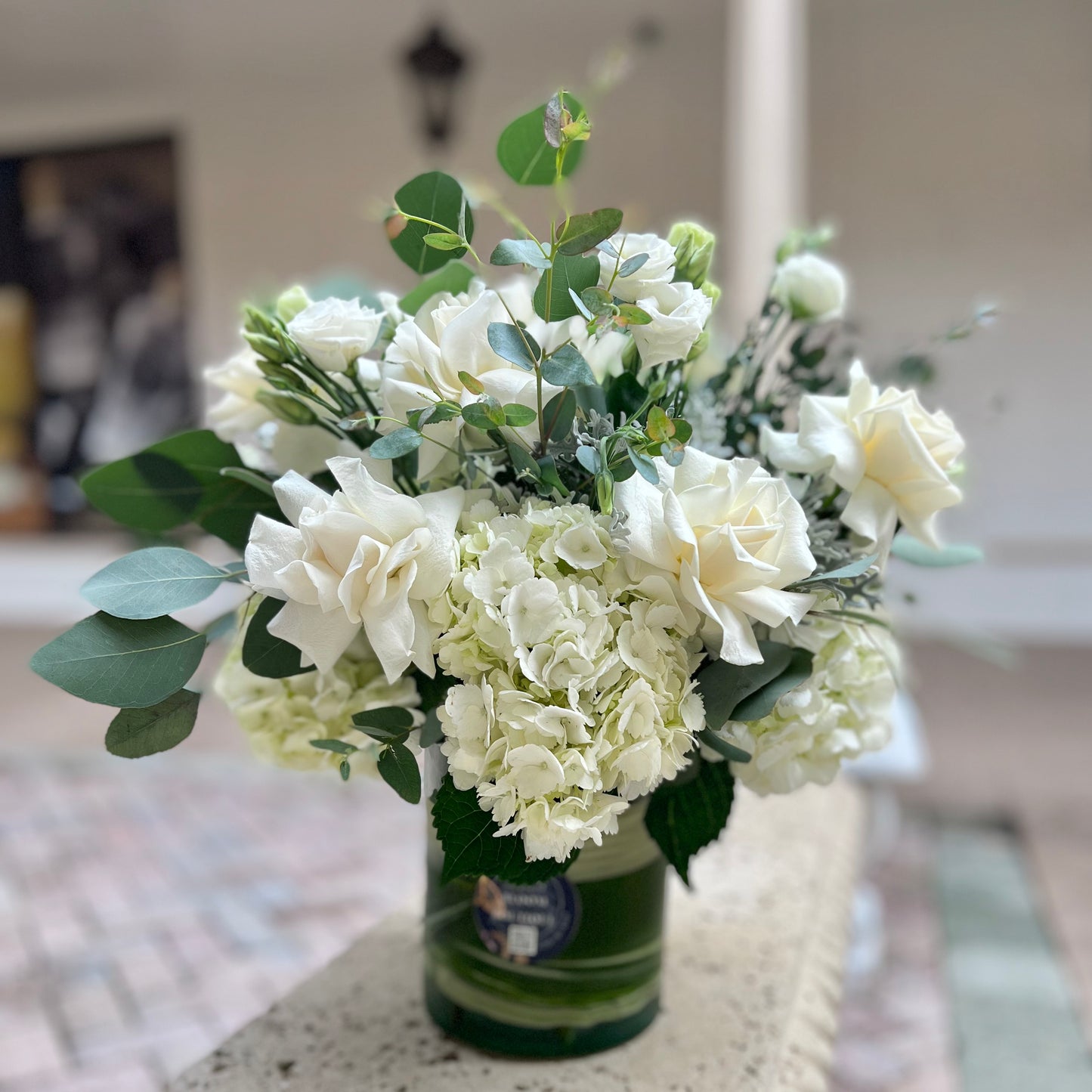 A gorgeous vase of flowers like roses, hydrangeas, lisianthus and a dash of greenery