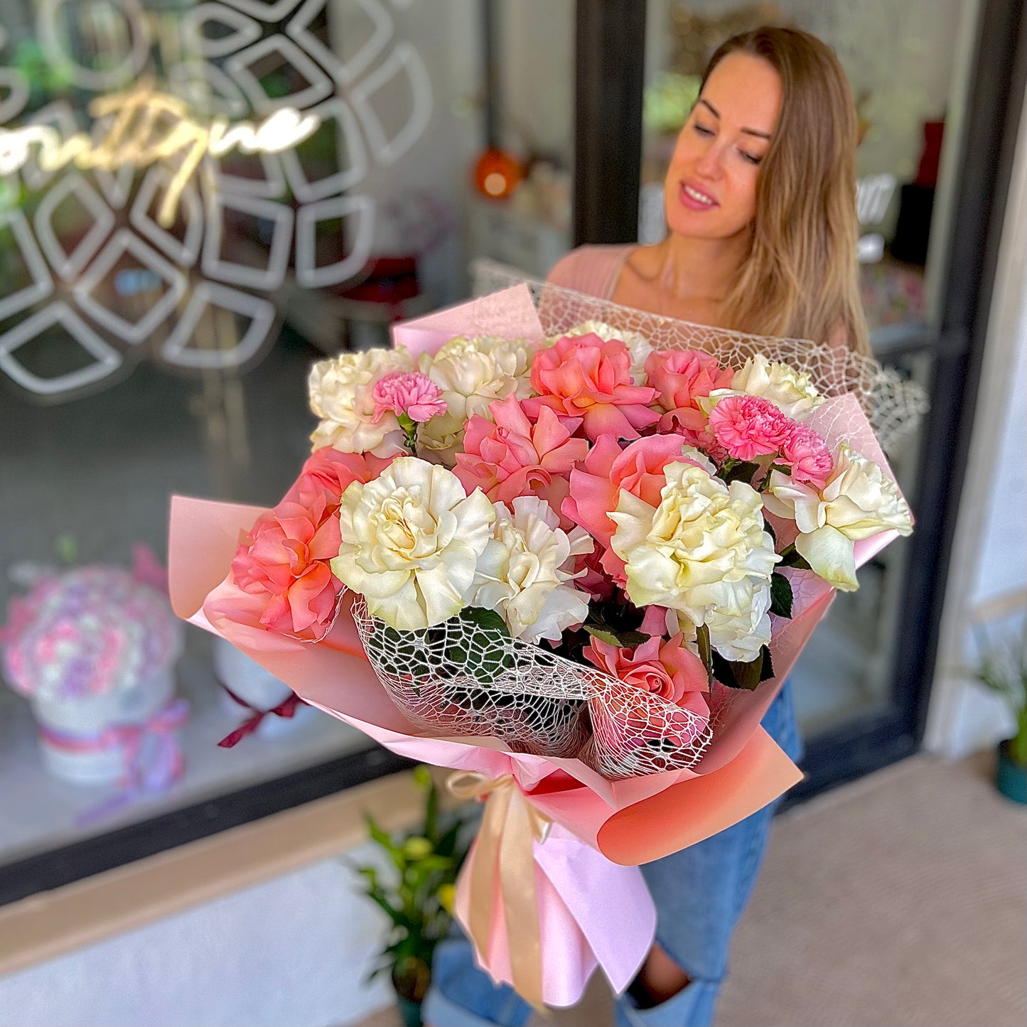 Beautiful pink and white flowers in pink tissue paper being held by a women with brown hair 