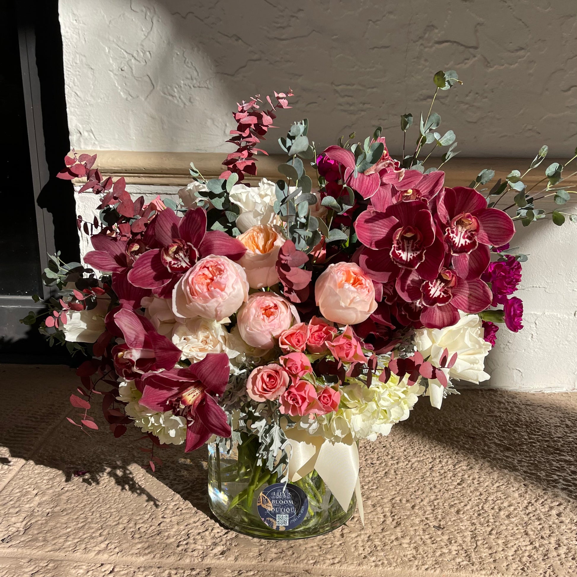 Roses of different shades, orchids, hydrangeas and some greenery in a vase
