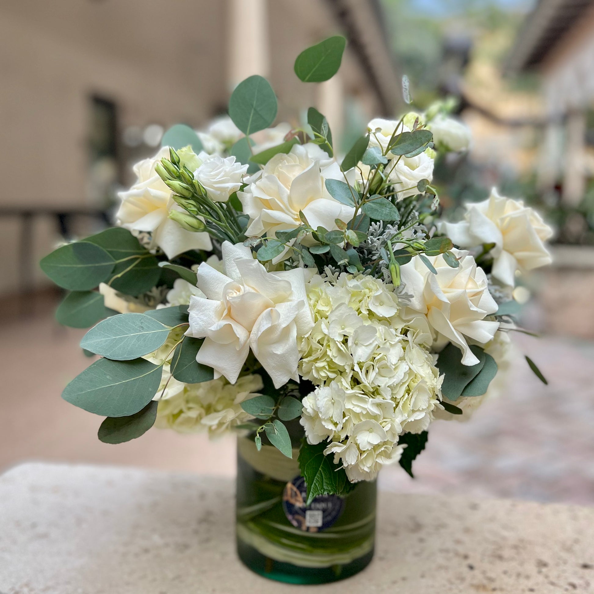 A beautiful vase with white flowers on a concrete bench