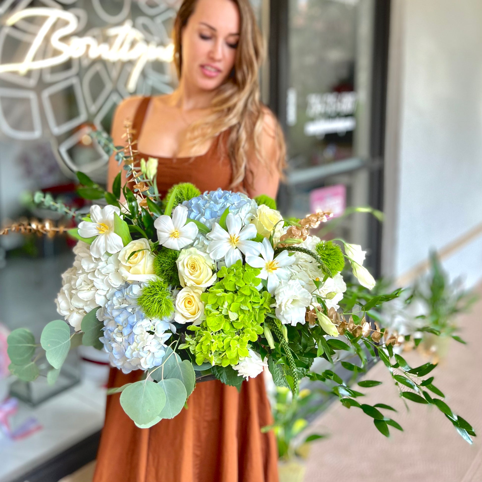 Women in brown dress holding flower bouquet with beautiful blue hydrangea