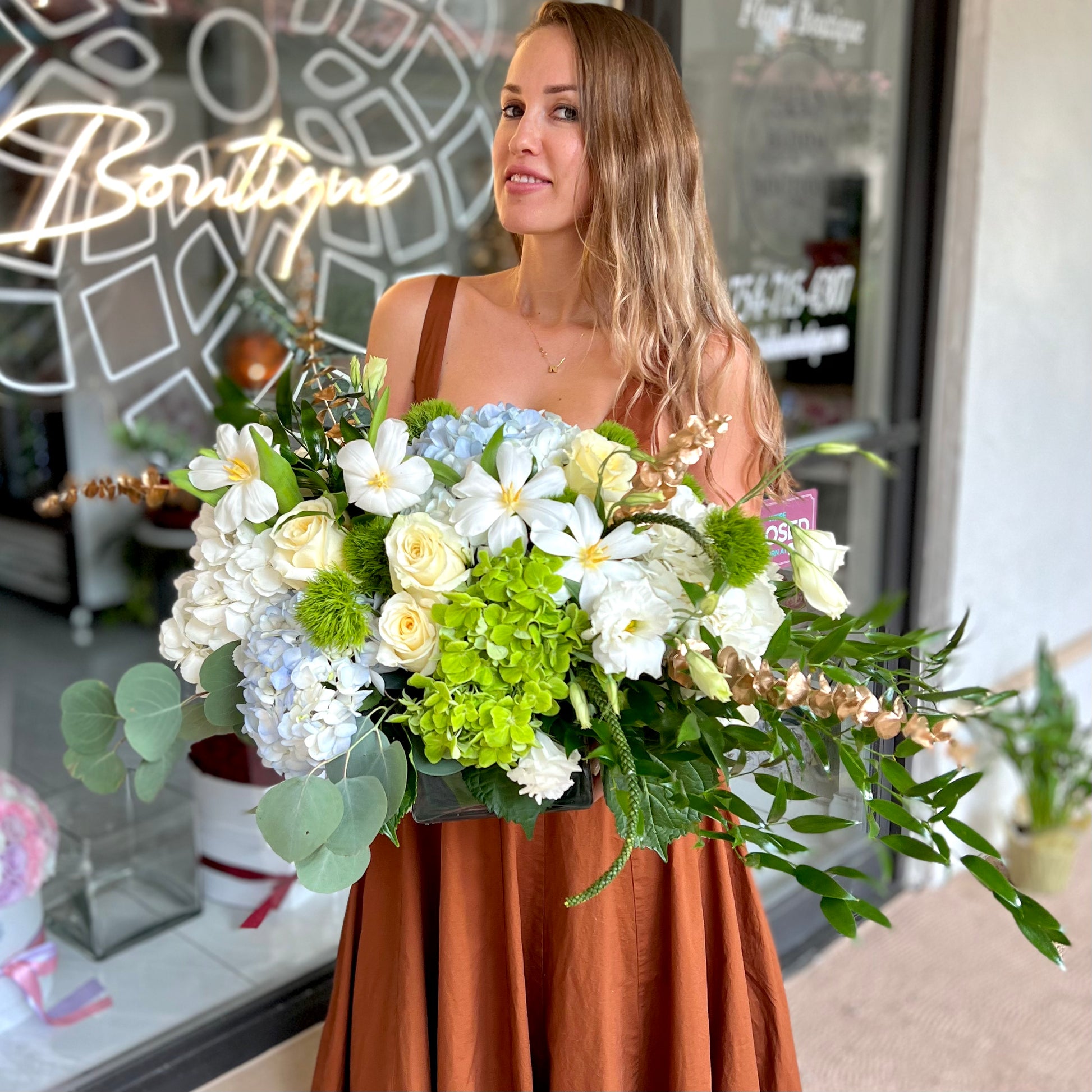 Long hair women in store front holding colorful tulips bouquet with blue hydrangea