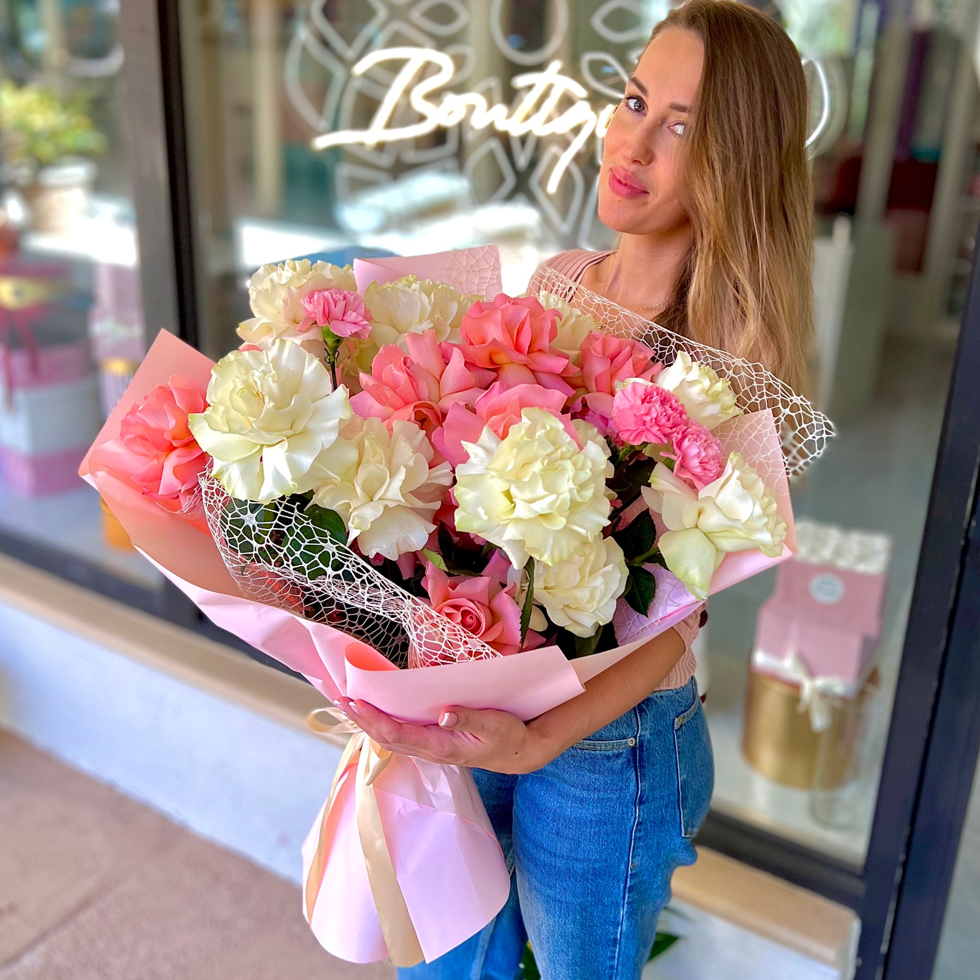 Romantic color flowers in pink tissue paper being displayed with a women with brown hair 